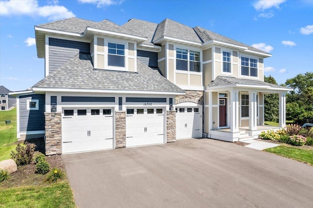 view of front of property with stone siding, roof with shingles, driveway, and an attached garage