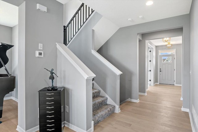 stairway with a notable chandelier, baseboards, and wood finished floors