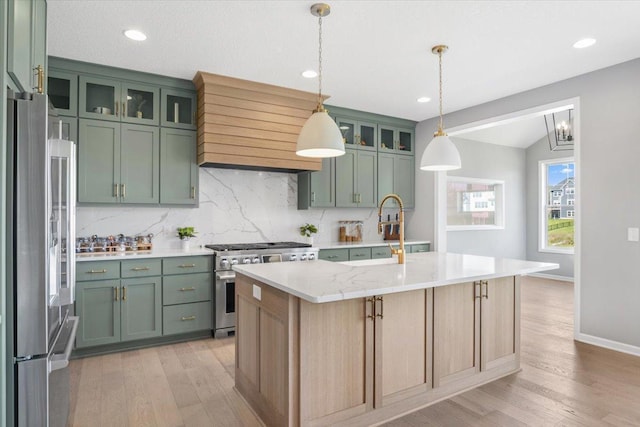 kitchen with light wood-style floors, green cabinets, appliances with stainless steel finishes, decorative backsplash, and custom range hood