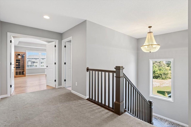 hallway featuring carpet floors, an upstairs landing, and baseboards