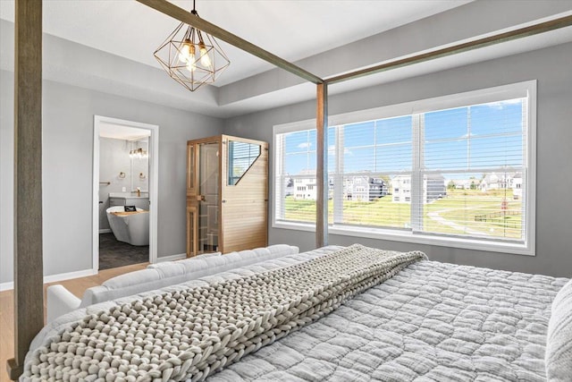 bedroom with baseboards, a notable chandelier, and ensuite bathroom