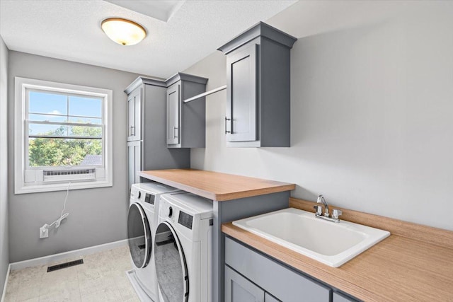 laundry room featuring visible vents, cabinet space, a sink, a textured ceiling, and washer and dryer