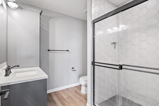 bathroom with toilet, a shower stall, and wood finished floors