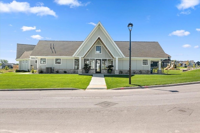 view of front of house with a shingled roof, board and batten siding, a front lawn, and central AC unit