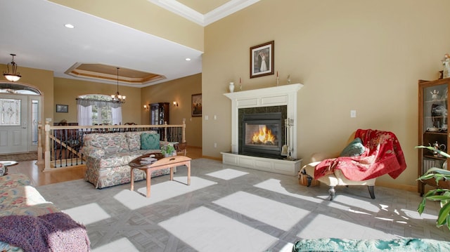 living room with ornamental molding, a high end fireplace, a raised ceiling, and baseboards