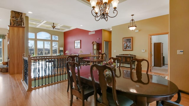 dining space featuring visible vents, coffered ceiling, wood finished floors, beam ceiling, and ceiling fan with notable chandelier