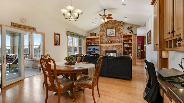 dining area with vaulted ceiling, light wood finished floors, ceiling fan with notable chandelier, and a fireplace