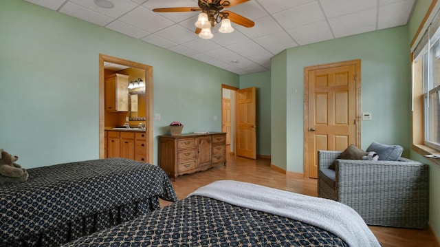 bedroom featuring a paneled ceiling, a sink, ensuite bath, and light wood finished floors