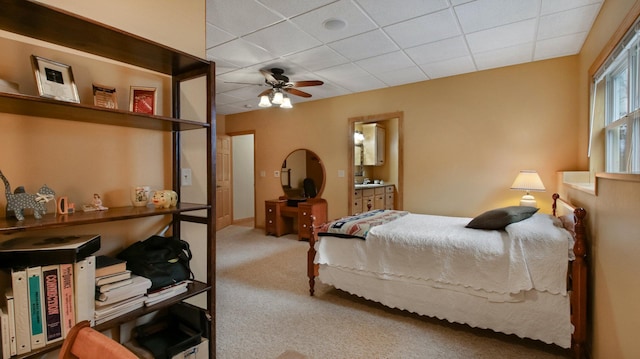 bedroom with a paneled ceiling, connected bathroom, and carpet flooring