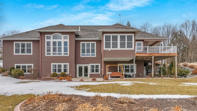 snow covered rear of property featuring a lawn and a wooden deck