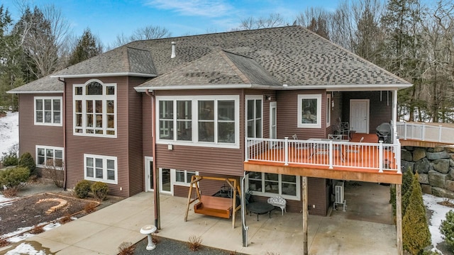 back of house featuring a deck, a patio, and roof with shingles