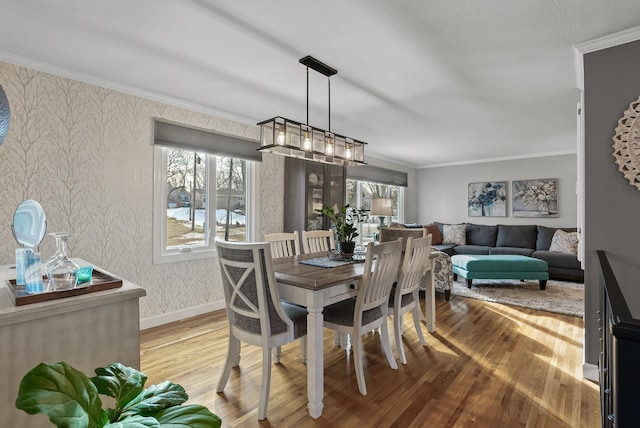 dining area with wallpapered walls, crown molding, baseboards, a chandelier, and wood finished floors