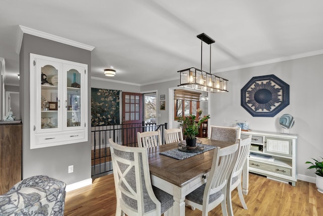 dining room featuring baseboards, light wood-style flooring, and crown molding