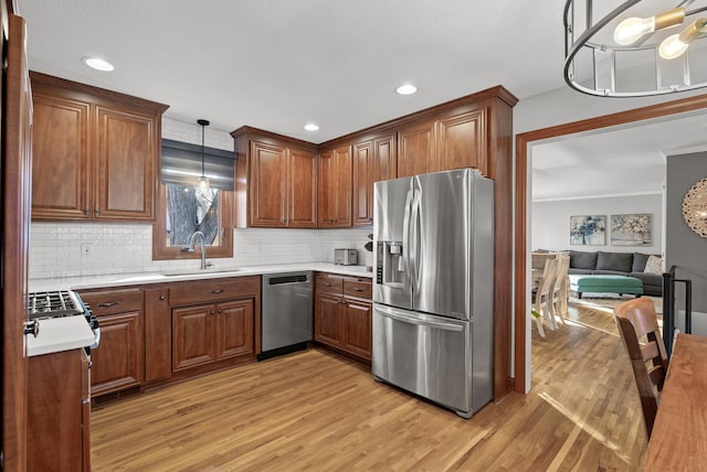 kitchen with light countertops, light wood finished floors, appliances with stainless steel finishes, and a sink