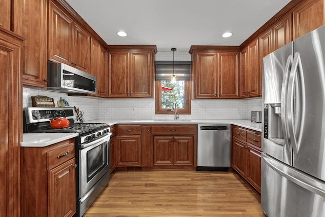 kitchen with light wood-style flooring, a sink, appliances with stainless steel finishes, brown cabinetry, and light countertops