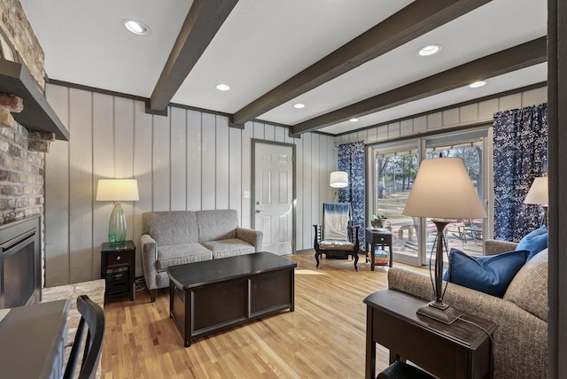 living room with a glass covered fireplace, beamed ceiling, recessed lighting, and light wood finished floors