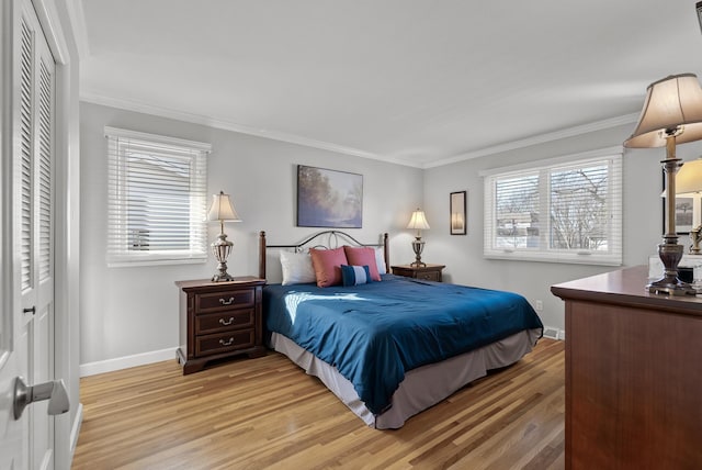 bedroom featuring a closet, light wood-type flooring, baseboards, and ornamental molding