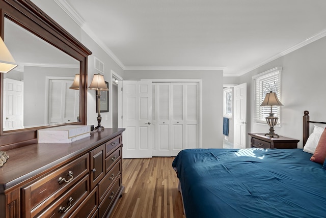 bedroom with a closet, visible vents, ornamental molding, and wood finished floors