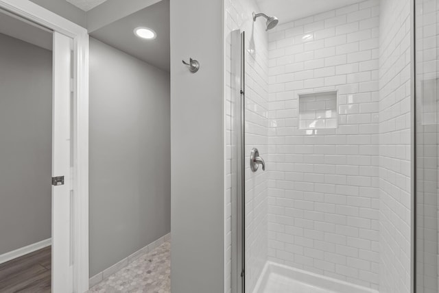 bathroom with a shower stall and baseboards