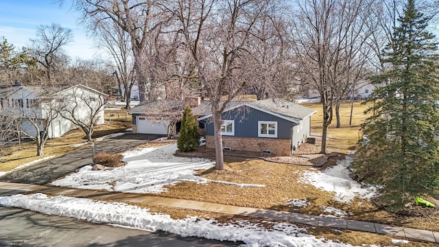 view of front of property featuring brick siding, a garage, driveway, and a chimney