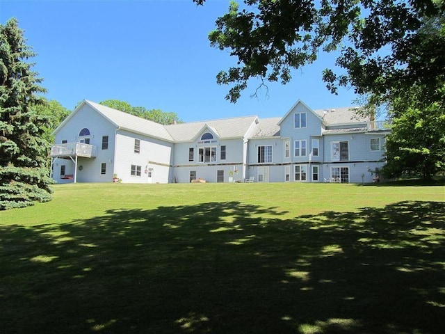 rear view of property featuring a lawn and a balcony