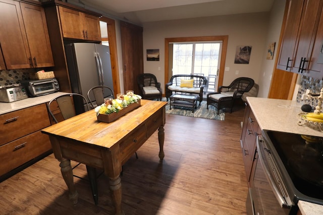 kitchen featuring dark wood-style floors, a toaster, light countertops, backsplash, and appliances with stainless steel finishes