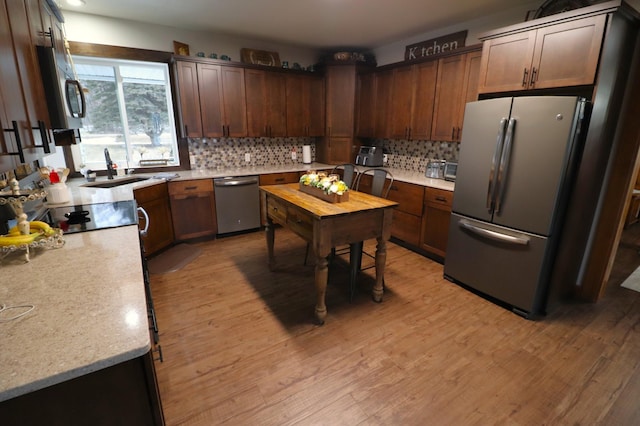 kitchen featuring stainless steel appliances, light countertops, a sink, and light wood-style flooring