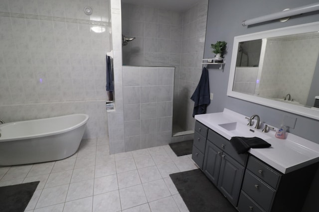 bathroom featuring tile patterned flooring, vanity, tile walls, a freestanding bath, and walk in shower