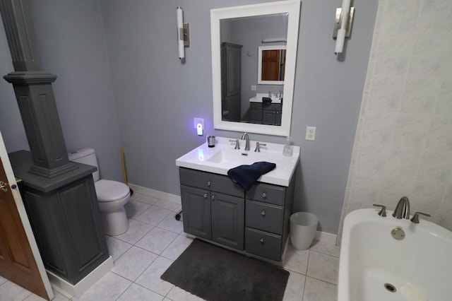 full bathroom featuring toilet, a bathing tub, vanity, baseboards, and tile patterned floors