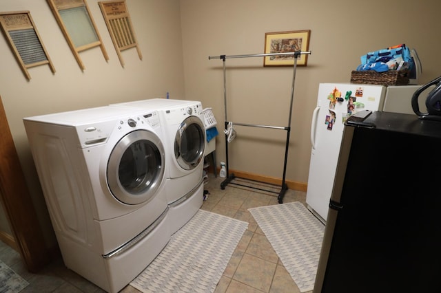 laundry room featuring laundry area, light tile patterned flooring, washing machine and dryer, and baseboards