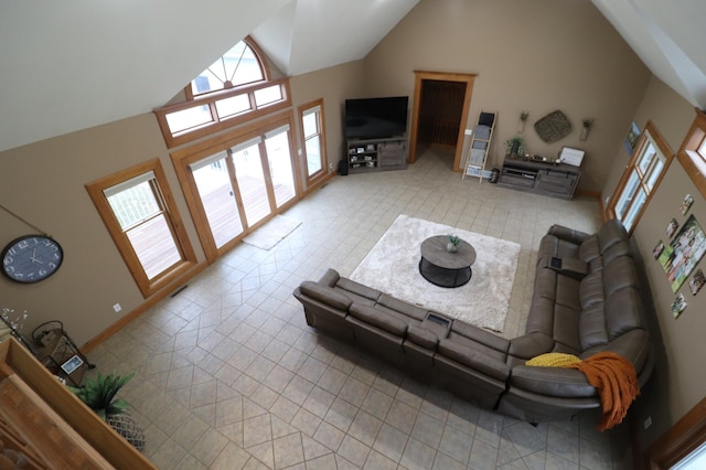 tiled living area featuring high vaulted ceiling and baseboards