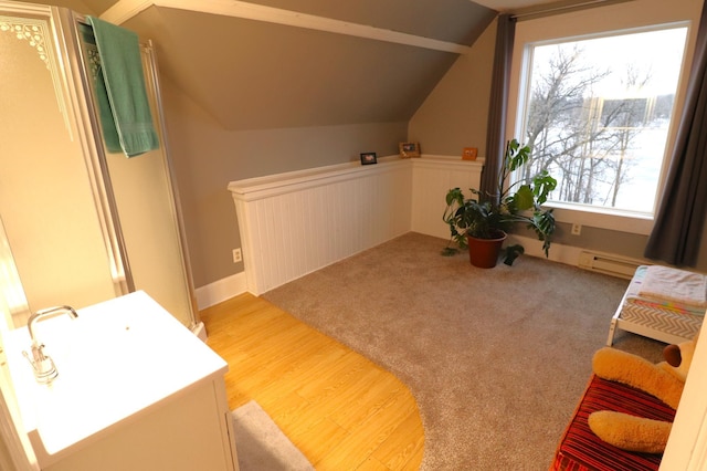 interior space with vaulted ceiling, a baseboard radiator, wood finished floors, and carpet