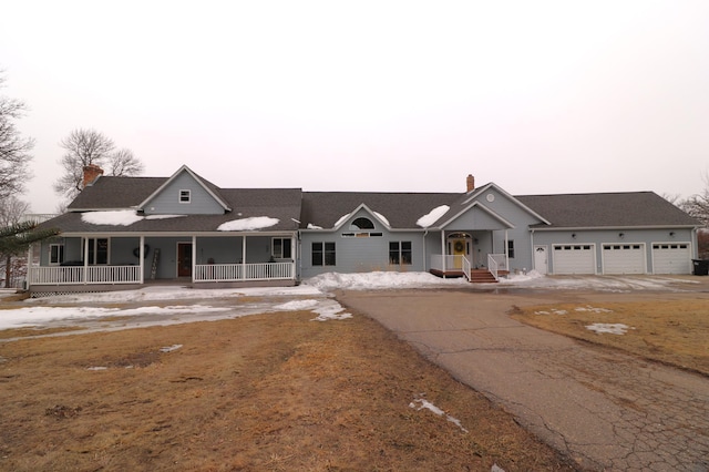 view of front of house with covered porch, driveway, and a chimney