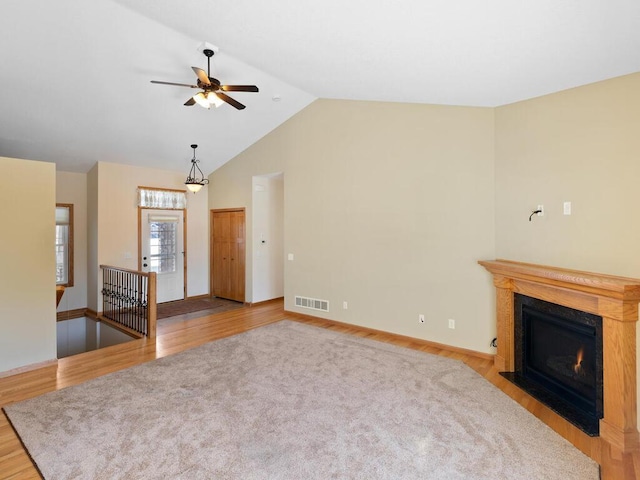 unfurnished living room with visible vents, a fireplace with flush hearth, lofted ceiling, and wood finished floors