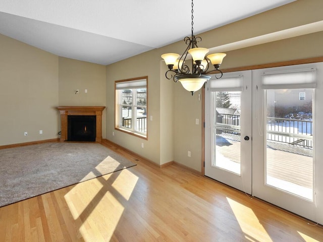 entryway with a chandelier, baseboards, a lit fireplace, and light wood-style flooring