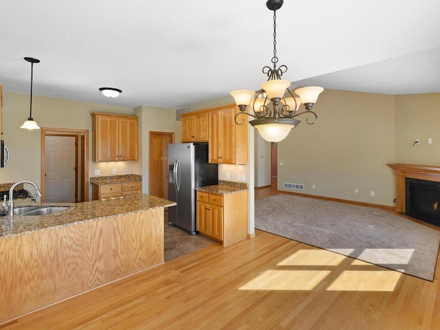 kitchen with visible vents, a fireplace with flush hearth, light wood-style flooring, a sink, and stainless steel appliances