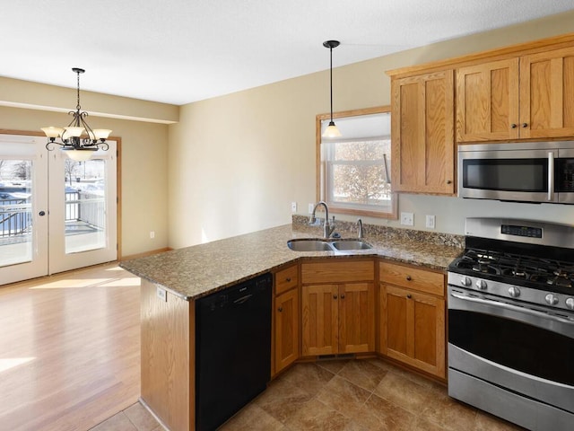 kitchen with a sink, a peninsula, light stone counters, and stainless steel appliances