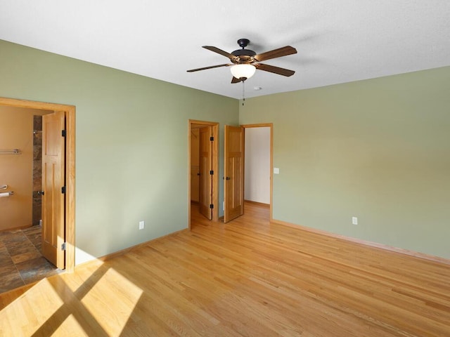 unfurnished bedroom featuring ceiling fan, baseboards, wood finished floors, and a spacious closet