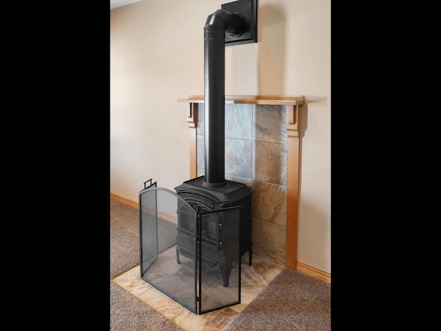 interior details featuring a wood stove, carpet, and baseboards