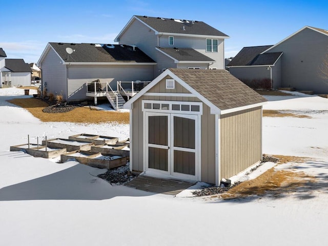 snow covered structure featuring an outbuilding and a storage unit