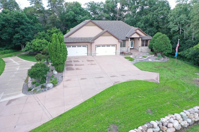 view of front of home featuring concrete driveway, stone siding, stucco siding, an attached garage, and a front yard