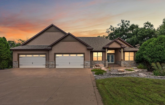 view of front facade with a garage, driveway, stone siding, french doors, and stucco siding