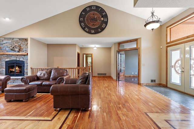 living room featuring french doors, a fireplace, visible vents, high vaulted ceiling, and hardwood / wood-style floors