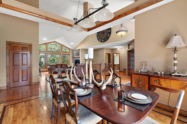 dining area with high vaulted ceiling, a fireplace, and wood-type flooring