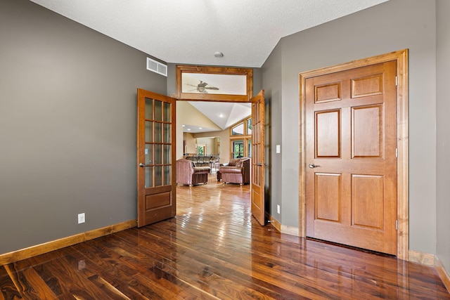 spare room featuring dark wood-style floors, visible vents, vaulted ceiling, and baseboards