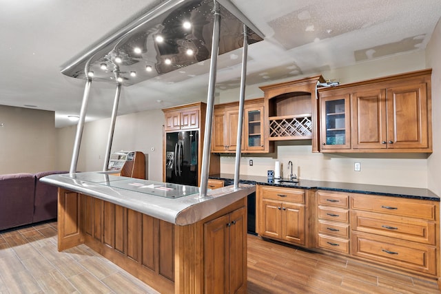 kitchen featuring brown cabinetry, a kitchen island, glass insert cabinets, wood tiled floor, and black appliances