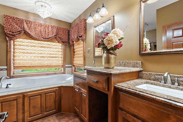 bathroom with tile patterned flooring, a notable chandelier, a textured ceiling, vanity, and a bath