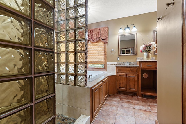 bathroom featuring tile patterned flooring, a garden tub, and vanity