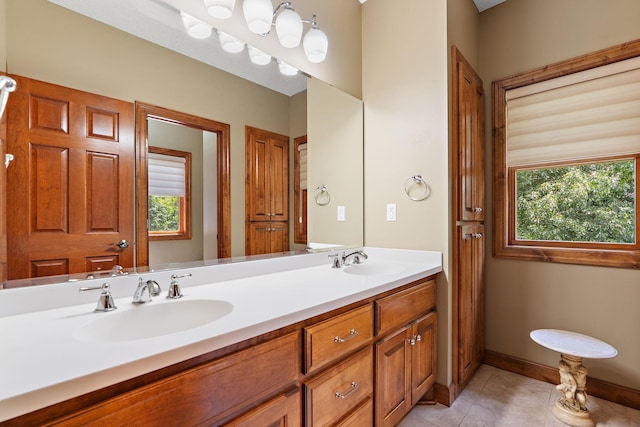 full bathroom with double vanity, tile patterned flooring, baseboards, and a sink