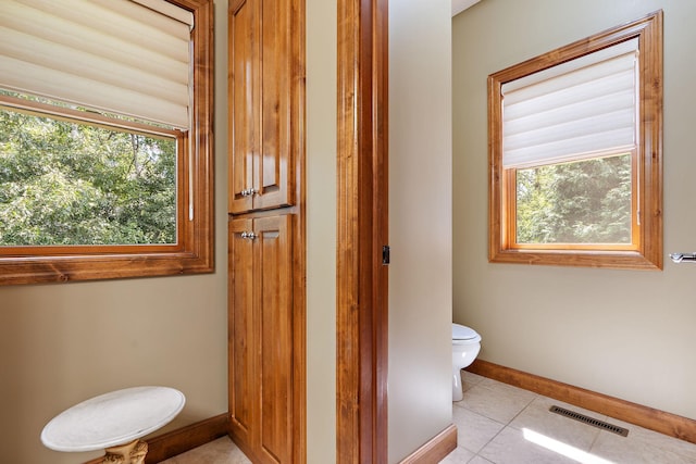 bathroom featuring toilet, a wealth of natural light, visible vents, and tile patterned floors